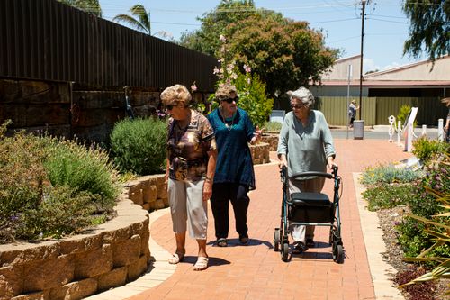 Older adults walking outdoors together with a rollator