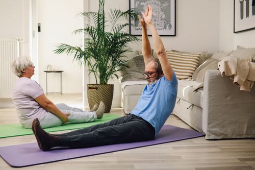 An older man exercising at home on a mat